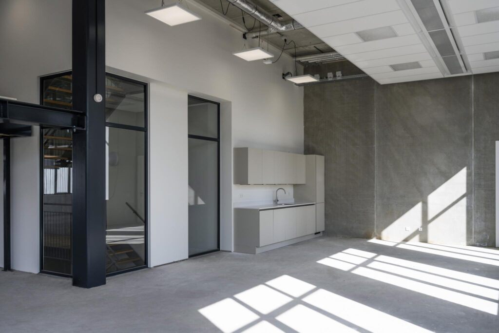 Modern industrial-style interior with a minimalist kitchenette and large windows on Paul van Vlissingenstraat.